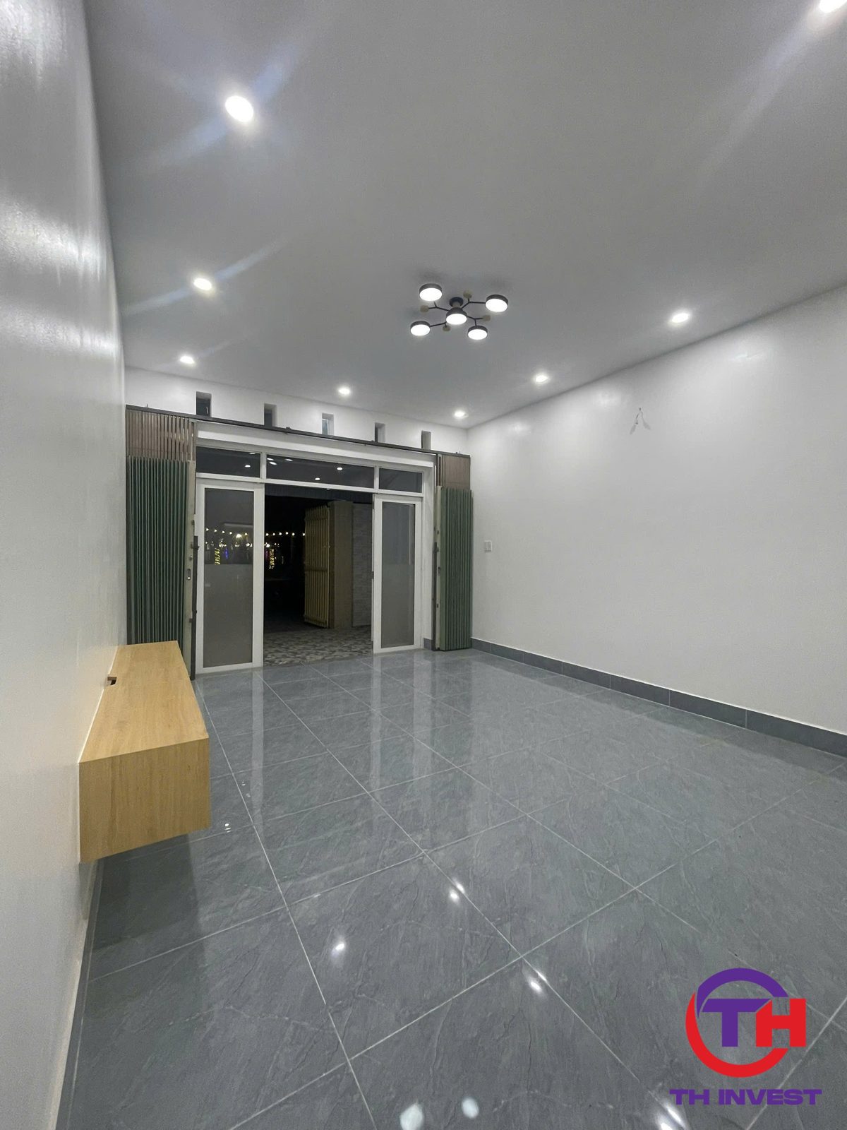 Phòng khách nhà trệt KĐT 5A nhìn ra cửa kính và công viên buổi tối